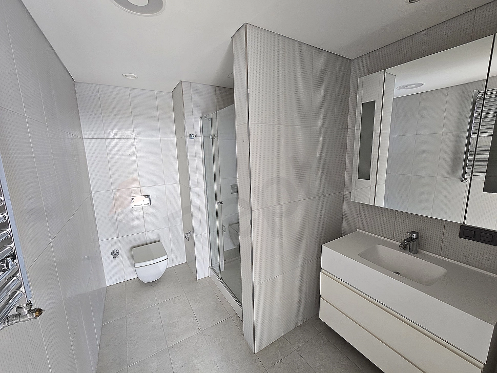 Modern tasarımlı, aydınlık ve geniş banyo. Beyaz seramikler, ahşap detaylar ve şık armatürler.