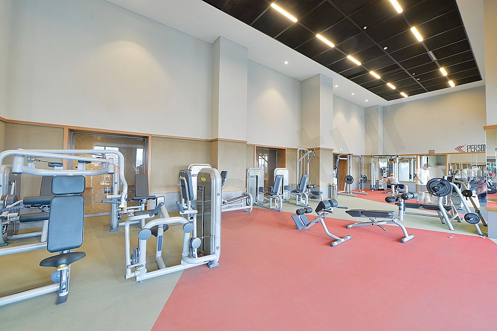 Modern spor salonu iç mekanı, fitness ekipmanları ve egzersiz yapan insanlar.
