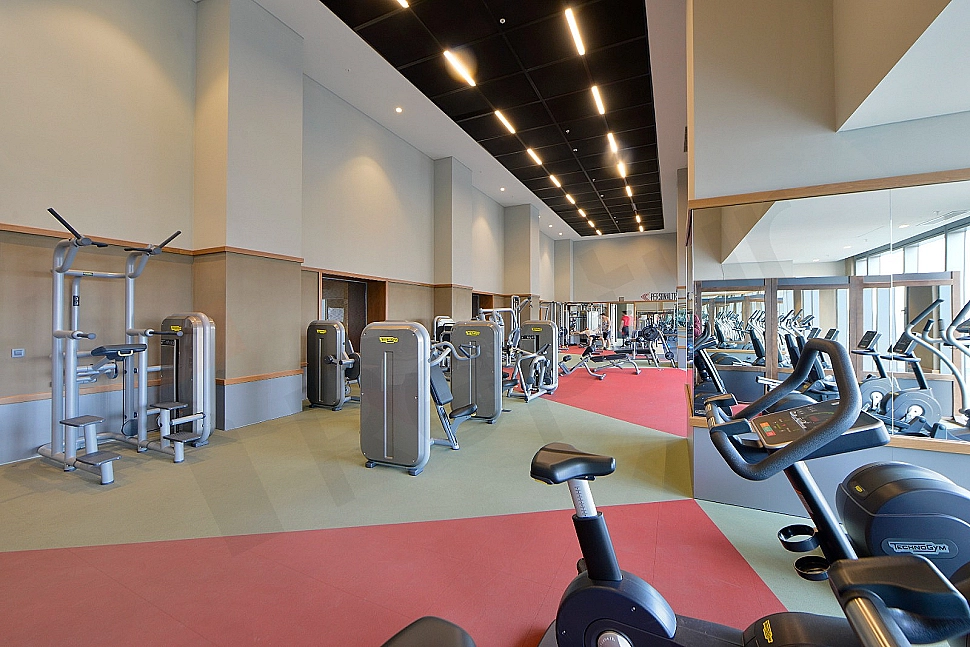 Modern spor salonu ekipmanları ile donatılmış iç mekan görüntüsü.