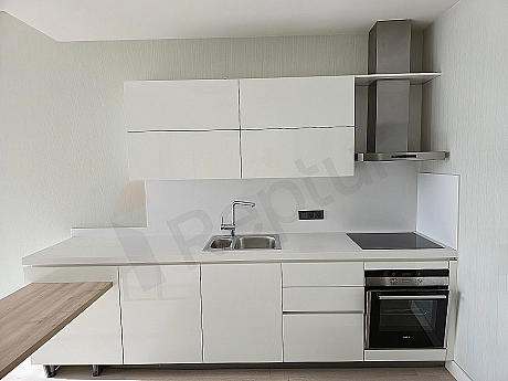 Modern beyaz mutfak dolapları, ahşap tezgahı ve ankastre beyaz eşyaları olan aydınlık mutfak.