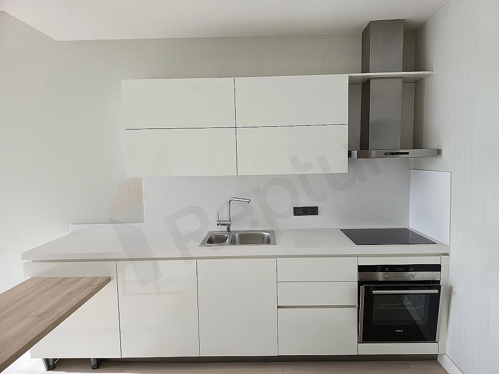 Modern beyaz mutfak dolapları, ahşap tezgahı ve ankastre beyaz eşyaları olan aydınlık mutfak.