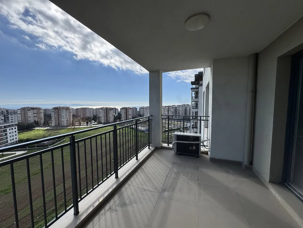 Modern bir binada geniş ve ferah tasarımlı bir daire balkonu.