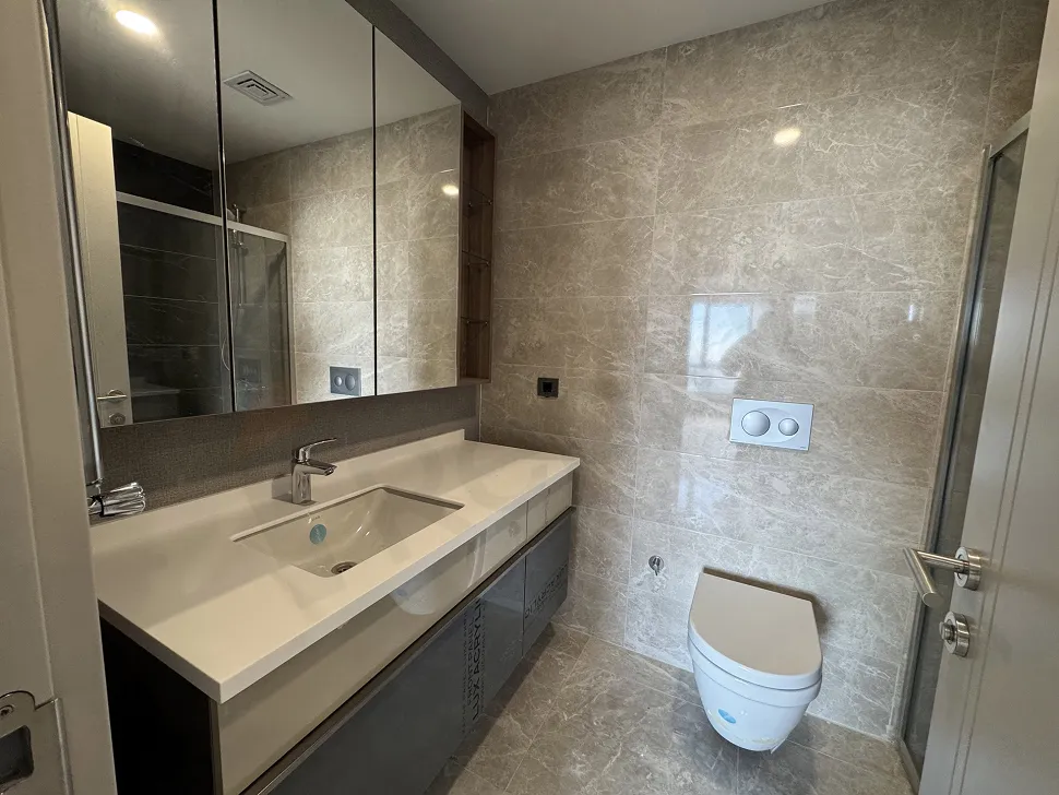 Modern ve şık seramiklerle döşenmiş, geniş ve aydınlık bir banyo iç mekânı.