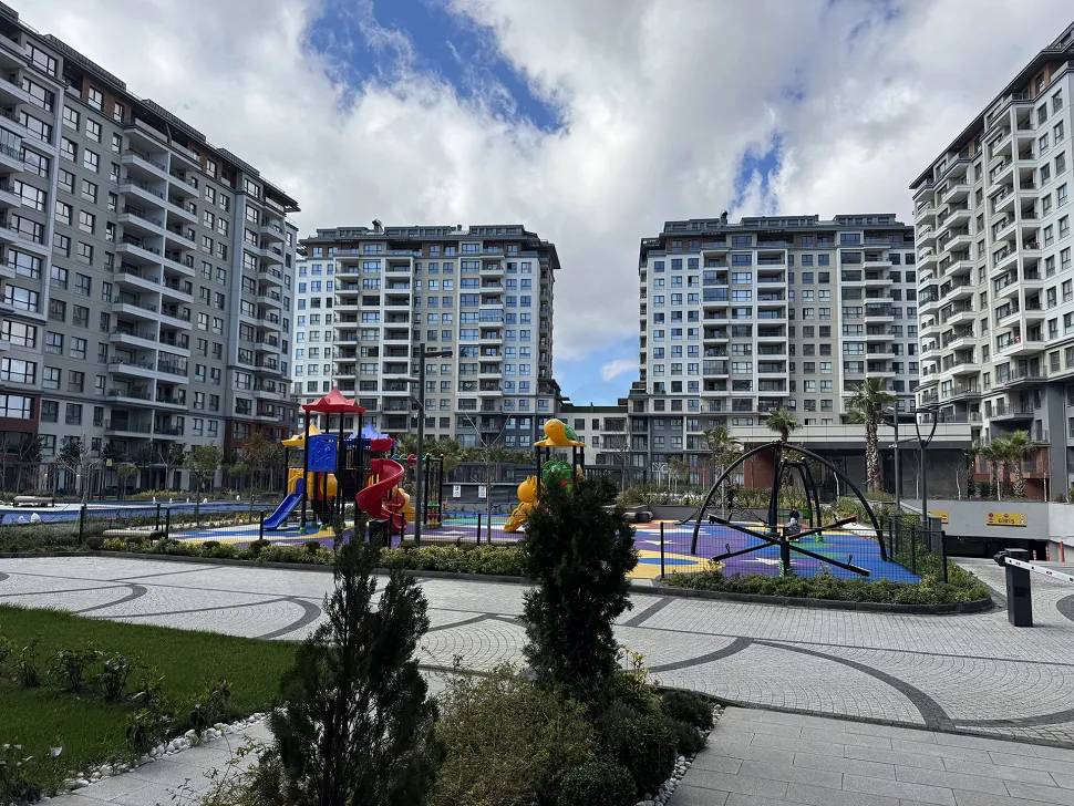 Modern peyzaj düzenlemesine ve yeşil alanlara sahip site bahçesi.