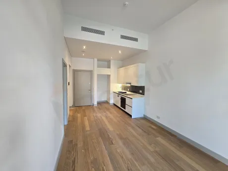 Şişli'de şehir manzaralı, geniş pencereli ve modern mimariye sahip aydınlık bir 1+1 dairenin oturma odası.