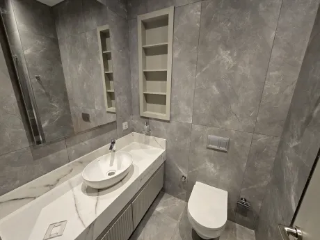 Modern banyo tasarımı, şık seramik döşemeler ve lavabo alanı.