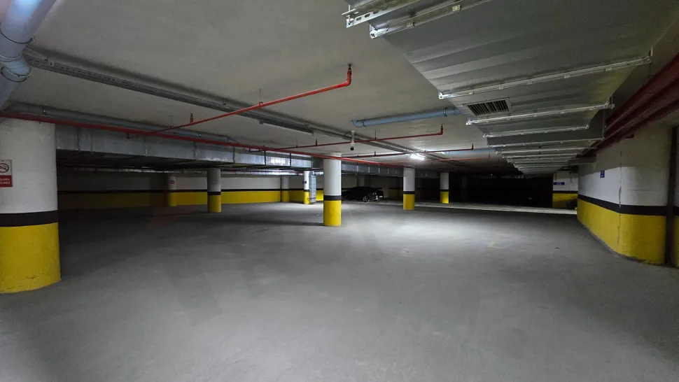 Modern mimariye sahip, geniş ve aydınlık kapalı otopark alanı görünümü.