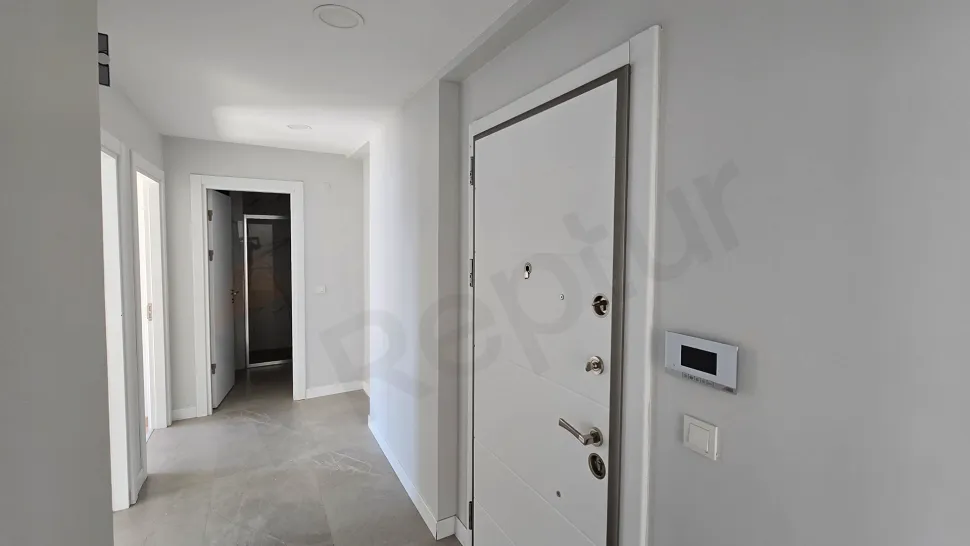 Modern bir binada yer alan şık ve aydınlık daire giriş kapısı ve antre bölümü.