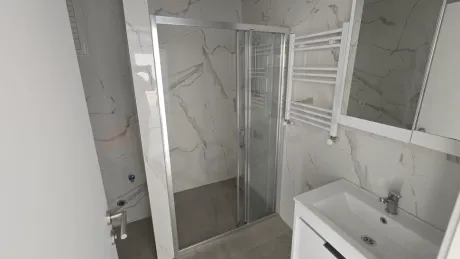 Modern tasarımlı, açık renkli seramiklerle kaplanmış ferah bir banyo iç mekanı.