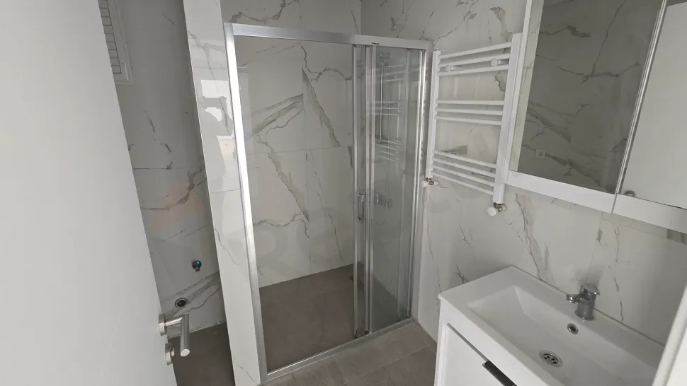 Modern tasarımlı, açık renkli seramiklerle kaplanmış ferah bir banyo iç mekanı.