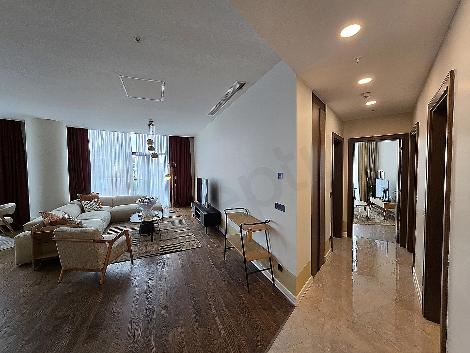 Şık ve modern oturma odası tasarımı, konforlu köşe koltuk, ahşap detaylar ve doğal ışık.
