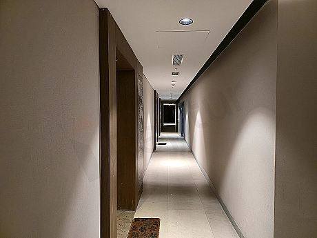 Modern daire koridoru, ahşap zemin, beyaz duvarlar, gömme dolaplar, aydınlatma detayları.
