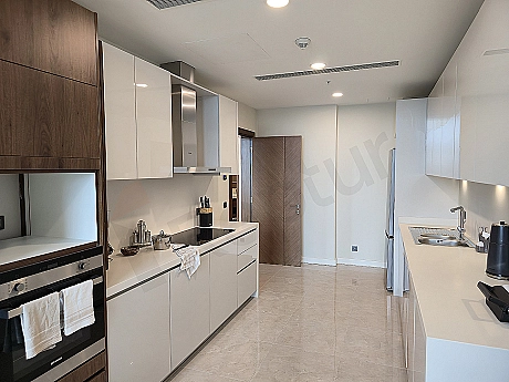 Modern beyaz mutfak dolapları, ankastre fırın ve ocak içeren geniş ve aydınlık bir mutfak.