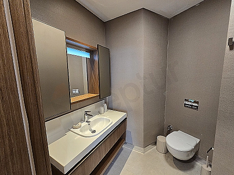 Modern tasarımlı, beyaz seramik lavabolu ve geniş aynalı lüks banyo.