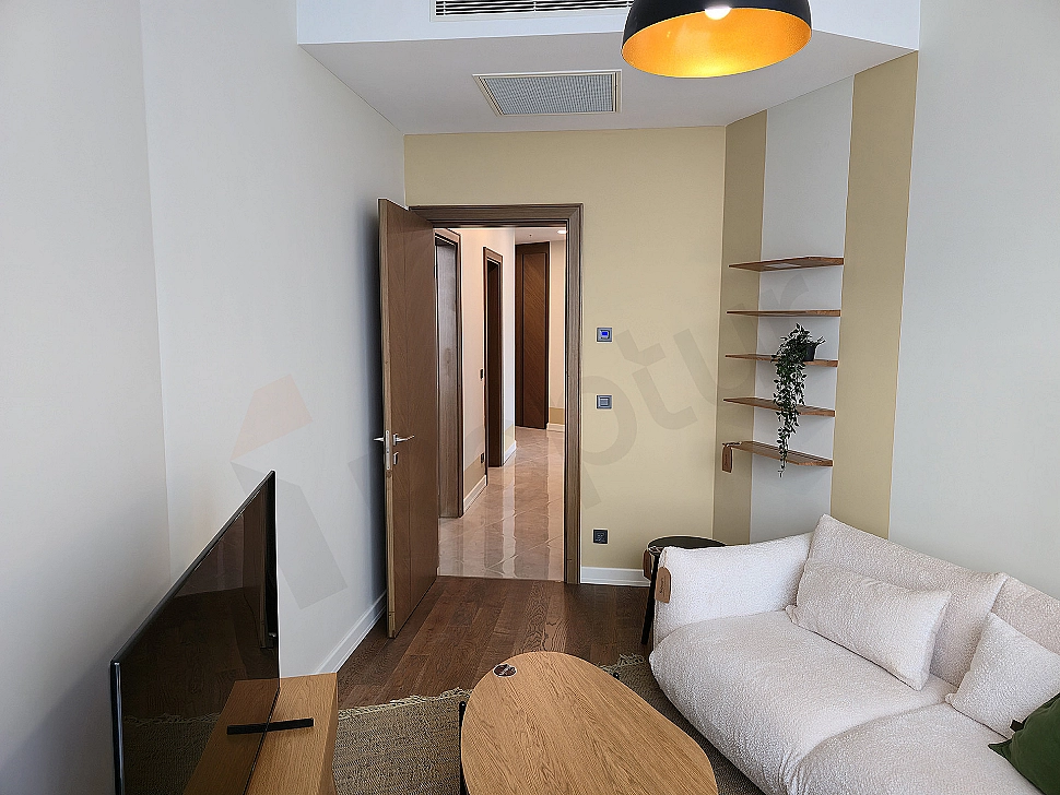 Modern çalışma odası: ahşap masa, ergonomik sandalye, kitaplık ve şehir manzaralı pencere.