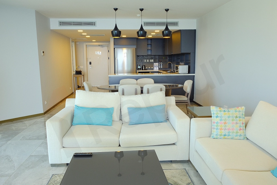Modern tasarımlı, eşyalı oturma odası. Ferah pencerelerden gelen doğal ışıkla aydınlanmış, rahat koltuk takımları ve şık dekoratif unsurlarla donatılmış.