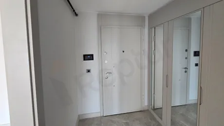 Modern bir binada yer alan geniş ve aydınlık daire girişi ve antre alanı.