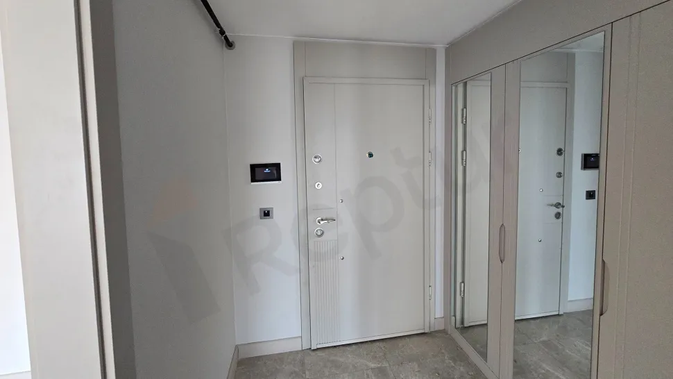 Modern bir binada yer alan geniş ve aydınlık daire girişi ve antre alanı.