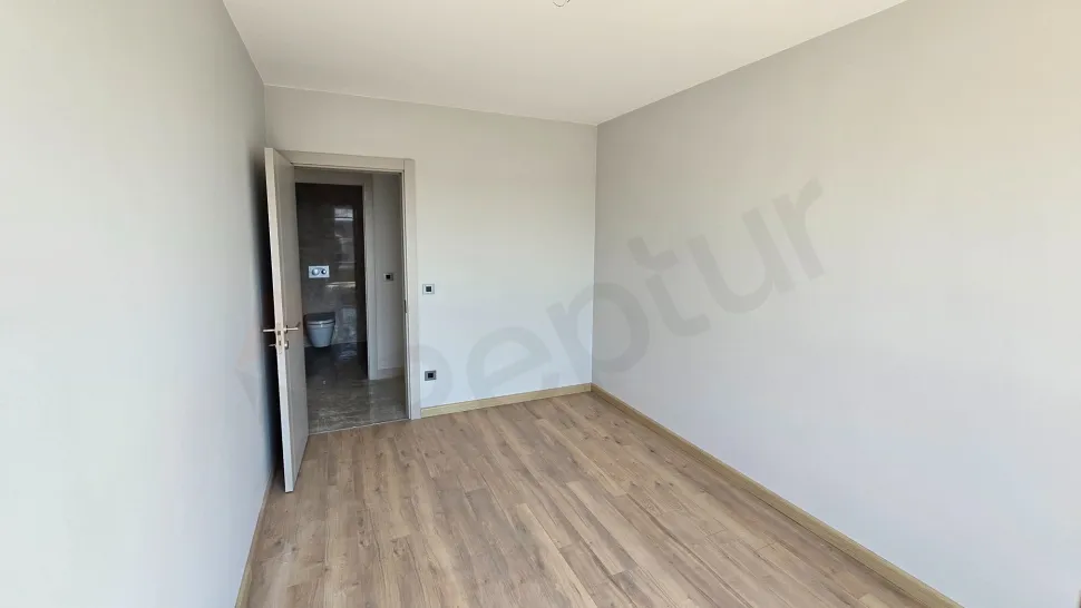 Geniş pencereli, gün ışığı alan ve parke zeminli modern bir yatak odası görünümü.