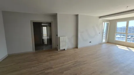 Geniş pencereli ve modern mimariye sahip aydınlık oturma odası alanı.