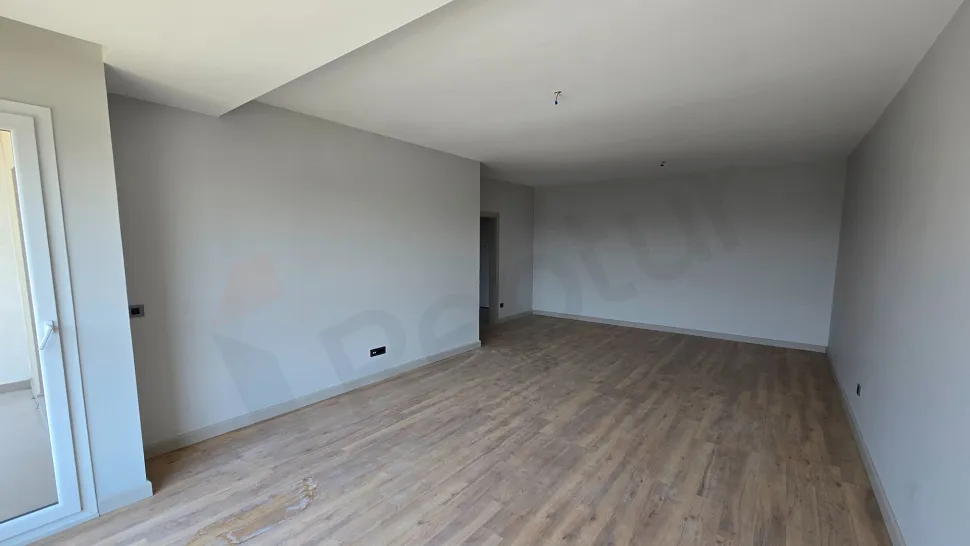 Modern bir dairenin geniş ve gün ışığı alan oturma odası görünümü.