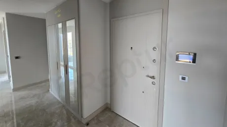 Modern bir yapıda yer alan lüks bir dairenin giriş kapısı ve antre alanı.