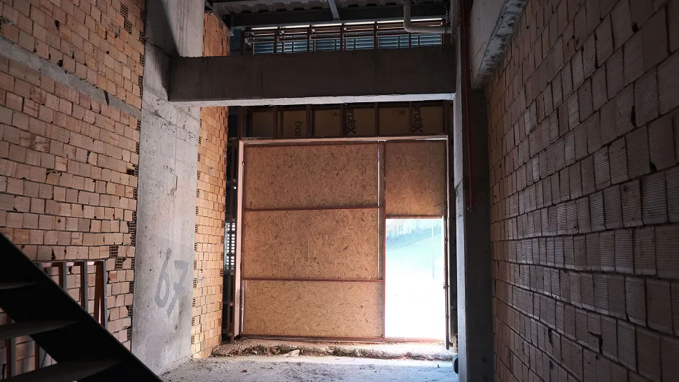 Geniş, beton zeminli ve kolonlu natamam dükkan iç mekanı.