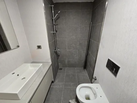 Modern tasarımlı, açık renk seramik kaplamalı ve aynalı banyo alanı.