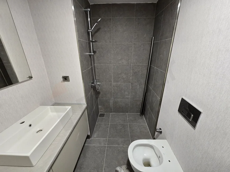 Modern tasarımlı, açık renk seramik kaplamalı ve aynalı banyo alanı.