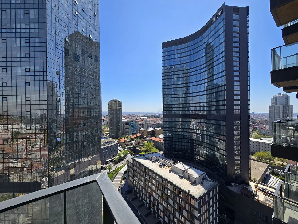 Şehir manzarasına sahip, modern bir rezidans dairesinin geniş ve açık balkon alanı.