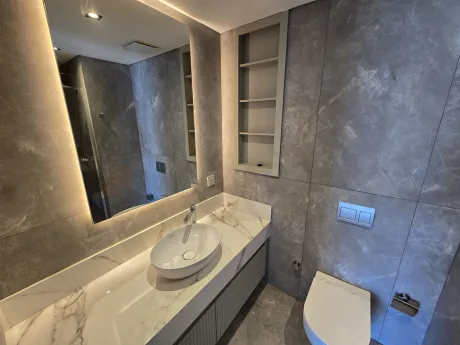 Modern tasarımlı banyo iç mekanı, şık seramikler ve lavabo alanı.