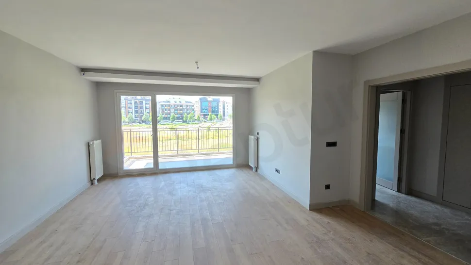 Modern mimariye sahip, geniş pencereli ve gün ışığı alan ferah bir boş oturma odası görünümü.