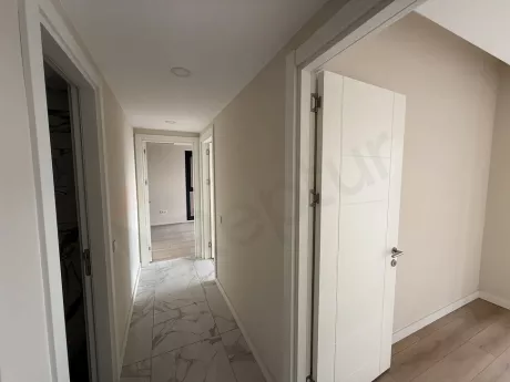 Yeni ve modern bir binanın iç mekanında yer alan geniş ve aydınlık koridor görünümü.