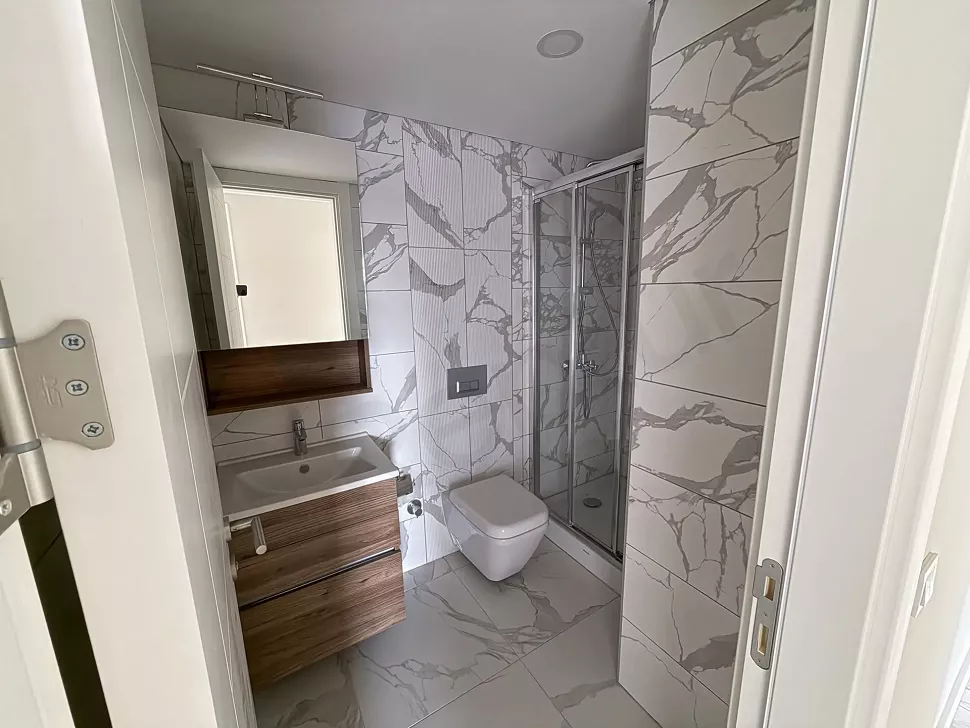 Modern ve şık tasarıma sahip, kaliteli armatürlerle donatılmış geniş bir banyo görseli.