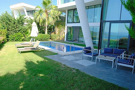 Bodrum'daki lüks villanın özenle tasarlanmış, geniş ve yeşil peyzajlı bahçesi.