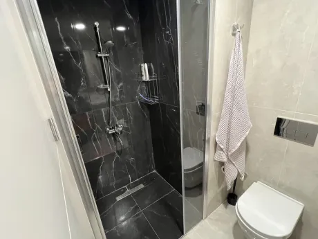 Modern tasarıma sahip şık banyo, kaliteli seramik kaplamalar ve geniş duş alanı.