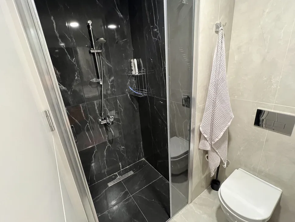 Modern tasarıma sahip şık banyo, kaliteli seramik kaplamalar ve geniş duş alanı.