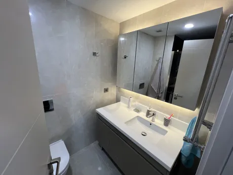 Modern ve şık tasarıma sahip, açık renkli fayanslarla kaplı banyo alanı.
