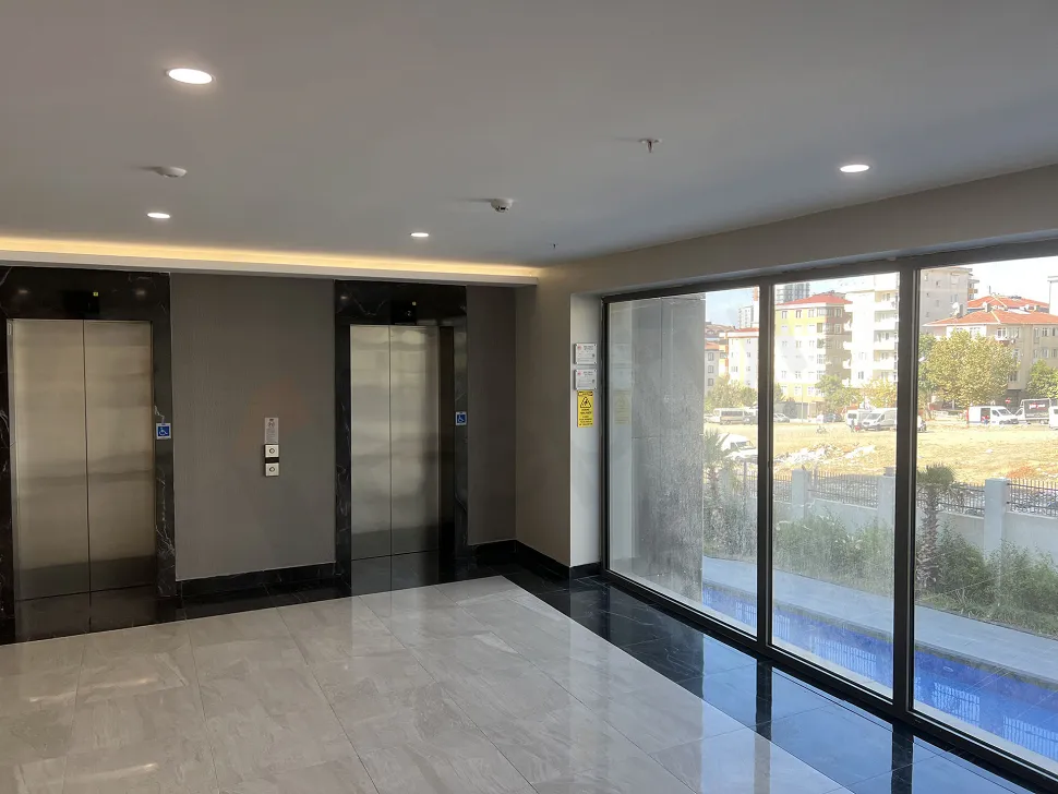 Modern tasarımlı, paslanmaz çelik yüzeyli ve aydınlatmalı bir asansör kabini iç görünümü.