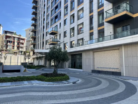 Modern bir site içerisinde peyzaj düzenlemesi yapılmış geniş ve yeşil bir bahçe alanı.