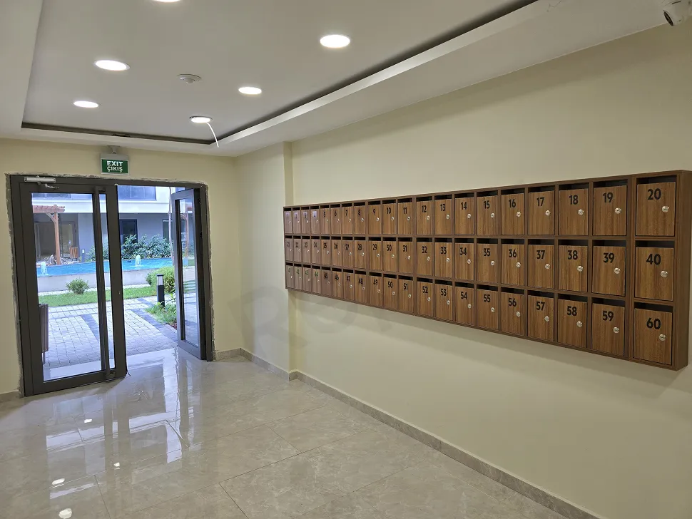 Modern ve şık tasarımlı, geniş pencereli ve lüks aydınlatmalı rezidans giriş lobisi.