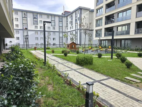 Modern bir konut sitesinin peyzajlı, yeşil bahçe alanı ve yürüyüş yolları.