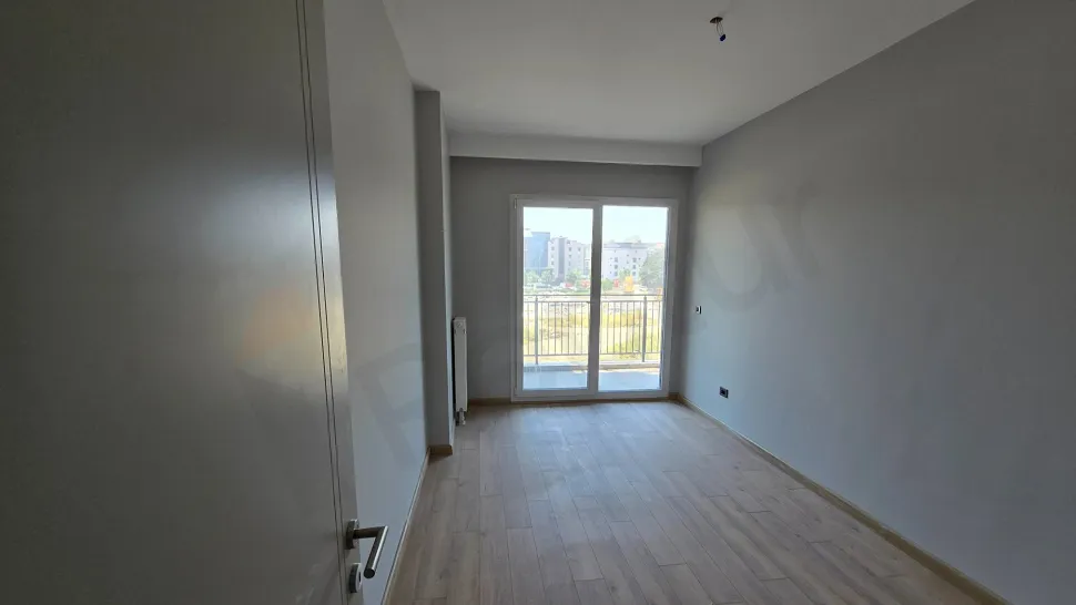 Modern bir binada yer alan geniş, ferah ve gün ışığı alan bir yatak odası görseli.