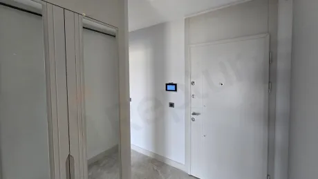 Modern bir dairenin geniş ve aydınlık giriş holü ile kapı alanı.