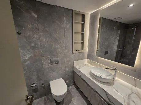 Modern tasarımlı, şık lavabo ve ayna detaylarına sahip geniş banyo alanı.