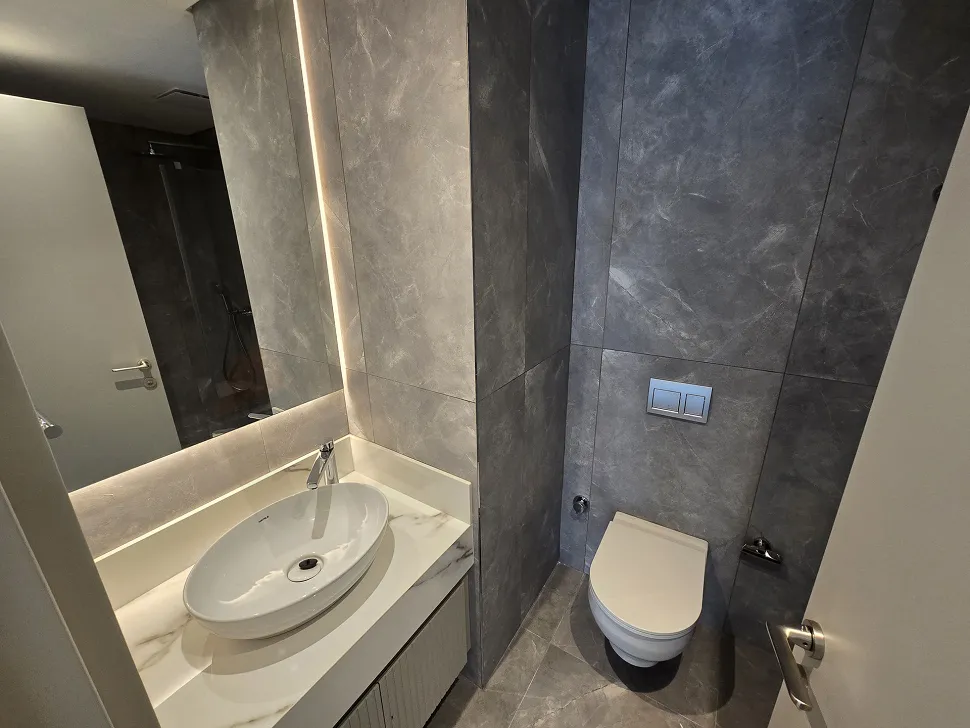 Modern tasarımlı, şık vitrifiye ve seramiklerle döşenmiş lüks bir banyo iç mekanı.