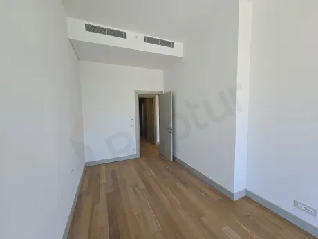 Modern tasarımlı, geniş pencereli ve şehir manzaralı aydınlık bir yatak odası.