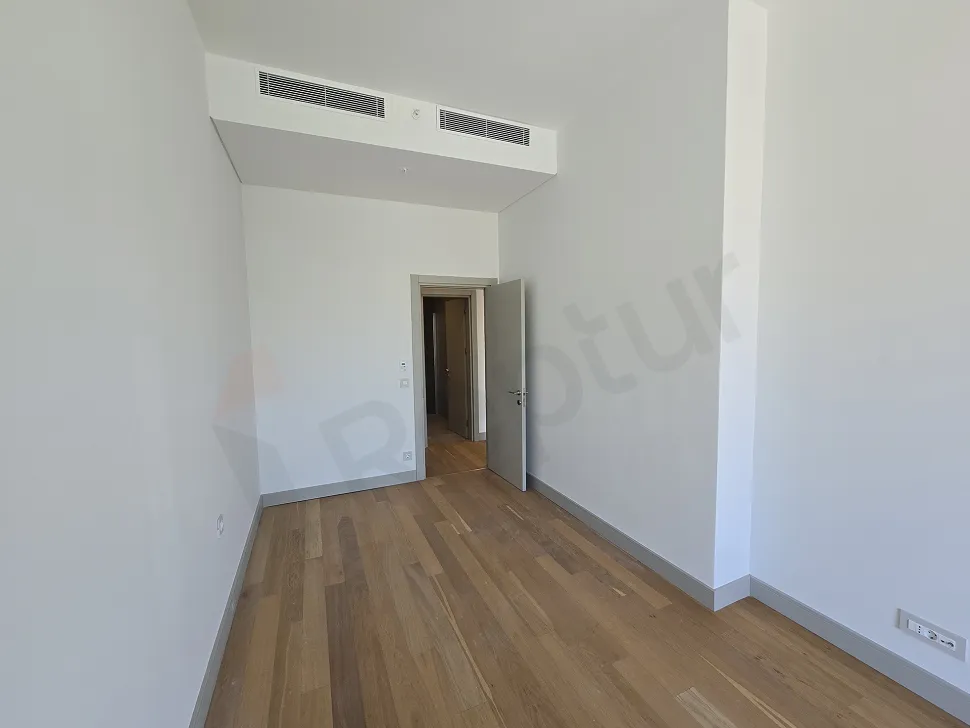 Modern tasarımlı, geniş pencereli ve şehir manzaralı aydınlık bir yatak odası.