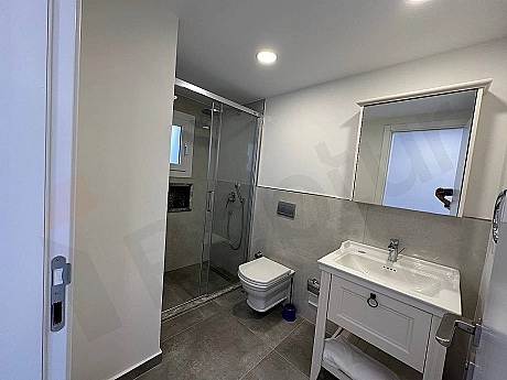 Modern tasarımlı, şık vitrifiye ve armatürlere sahip, temiz ve aydınlık bir banyo iç mekanı.