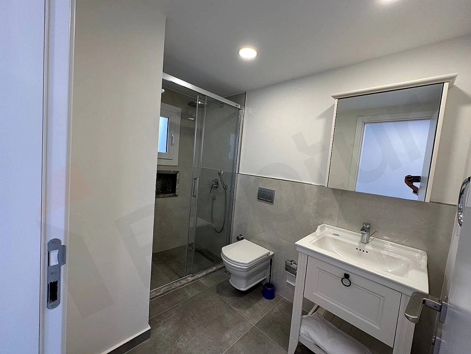 Modern tasarımlı, şık vitrifiye ve armatürlere sahip, temiz ve aydınlık bir banyo iç mekanı.